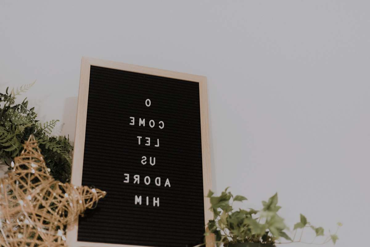 bible verse shallow focus photo of come let us adore him quote board with brown wooden frame prayer